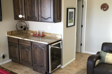 Inspiration for a small transitional single-wall home bar remodel in Phoenix with dark wood cabinets, granite countertops and stone slab backsplash