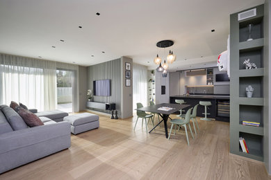 Foto di un ampio soggiorno minimalista con pareti grigie, parquet chiaro e TV a parete