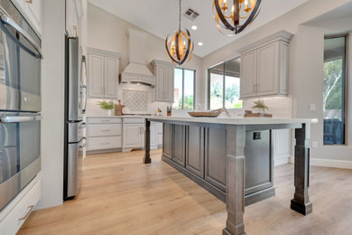 Example of a mid-sized transitional u-shaped eat-in kitchen design in Phoenix with an undermount sink, raised-panel cabinets, gray cabinets, quartz countertops, white backsplash, subway tile backsplash, stainless steel appliances, an island and white countertops