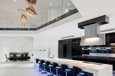 Expansive contemporary galley eat-in kitchen in Other with an undermount sink, flat-panel cabinets, marble benchtops, black splashback, glass sheet splashback, stainless steel appliances, ceramic floors and with island.