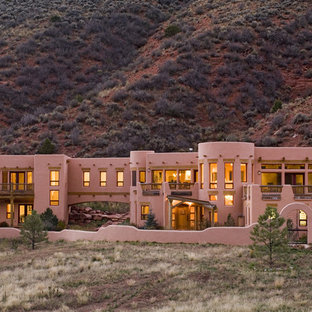 На фото: класса люкс двухэтажные, огромные фасады частных домов розового цвета в стиле фьюжн с облицовкой из самана и плоской крышей