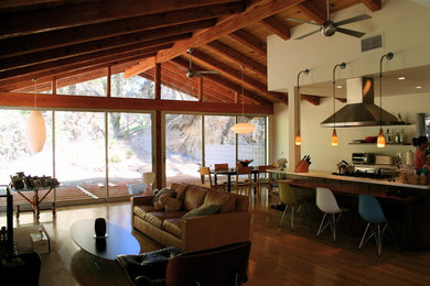 Example of a mid-sized single-wall light wood floor open concept kitchen design in Los Angeles with flat-panel cabinets, medium tone wood cabinets, stainless steel appliances and an island