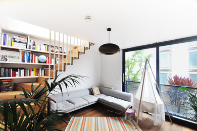 This is an example of a small contemporary open plan living room in London with medium hardwood flooring, white walls and no fireplace.