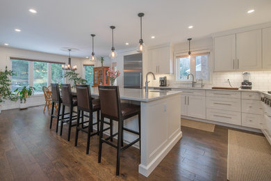 Mid-sized transitional l-shaped kitchen photo in Toronto with recessed-panel cabinets, white cabinets, quartzite countertops, white backsplash, subway tile backsplash, stainless steel appliances and an island