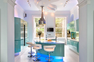 Photo of a large contemporary galley separate kitchen in London with an integrated sink, flat-panel cabinets, solid surface benchtops, green splashback, glass sheet splashback, stainless steel appliances, ceramic floors, with island and blue cabinets.