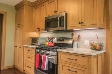 Inspiration for a small timeless medium tone wood floor and brown floor kitchen remodel in Oklahoma City with shaker cabinets, medium tone wood cabinets, no island, marble countertops, gray backsplash, glass tile backsplash, stainless steel appliances and gray countertops