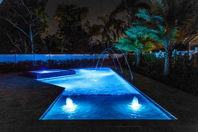 Photo of a large contemporary backyard custom-shaped pool in Miami with a hot tub and tile.