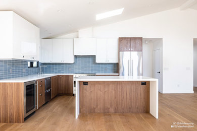 Photo of a mid-sized contemporary l-shaped eat-in kitchen in Denver with flat-panel cabinets, medium wood cabinets, quartz benchtops, blue splashback, ceramic splashback, stainless steel appliances, bamboo floors, with island, brown floor, white benchtop and vaulted.