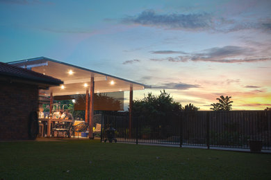 Design ideas for a large modern backyard patio in Brisbane with stamped concrete and a pergola.