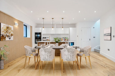 This is an example of a small traditional dining room in London with white walls, light hardwood flooring and panelled walls.