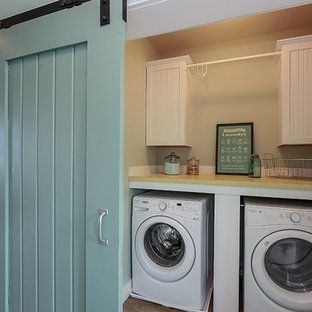 This is an example of a medium sized traditional single-wall laundry cupboard in Other with white cabinets, a side by side washer and dryer, yellow worktops and recessed-panel cabinets.