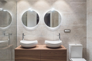 Foto de cuarto de baño principal contemporáneo de tamaño medio con armarios con paneles lisos, puertas de armario de madera oscura, baldosas y/o azulejos beige, baldosas y/o azulejos de cerámica, lavabo sobreencimera, encimera de madera, suelo beige y encimeras marrones