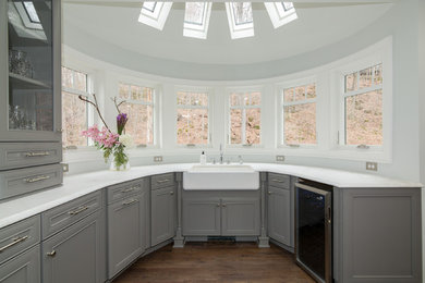 This is an example of a large u-shaped eat-in kitchen in New York with a farmhouse sink, beaded inset cabinets, grey cabinets, marble benchtops, white splashback, marble splashback, stainless steel appliances, dark hardwood floors, with island and brown floor.