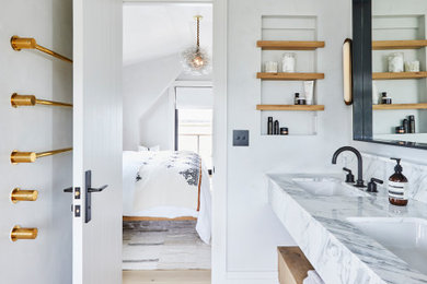 Immagine di una stanza da bagno boho chic con top in marmo, porta doccia a battente, due lavabi e mobile bagno incassato