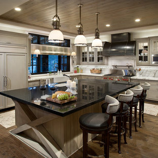 Design ideas for a country l-shaped kitchen in Sacramento with a farmhouse sink, shaker cabinets, grey cabinets, white splashback, panelled appliances and dark hardwood floors.