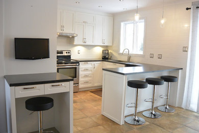 Trendy kitchen photo in Montreal with shaker cabinets, white cabinets, white backsplash, porcelain backsplash and an island