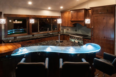 Example of a large l-shaped medium tone wood floor eat-in kitchen design in Seattle with a double-bowl sink, medium tone wood cabinets, granite countertops, blue backsplash, glass tile backsplash and an island
