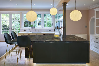 Mid-sized arts and crafts l-shaped open plan kitchen in London with flat-panel cabinets, marble benchtops, with island and brown benchtop.