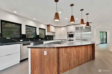 Inspiration for a large contemporary medium tone wood floor and gray floor enclosed kitchen remodel in Seattle with flat-panel cabinets, white cabinets, quartz countertops, stainless steel appliances, an island and black countertops