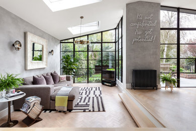 Mittelgroßes, Offenes Modernes Wohnzimmer ohne Kamin mit grauer Wandfarbe, hellem Holzboden, freistehendem TV, braunem Boden und gewölbter Decke in London
