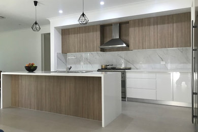 Design ideas for a large contemporary single-wall eat-in kitchen in Sydney with a double-bowl sink, flat-panel cabinets, medium wood cabinets, granite benchtops, beige splashback, subway tile splashback, stainless steel appliances, medium hardwood floors, with island and white benchtop.