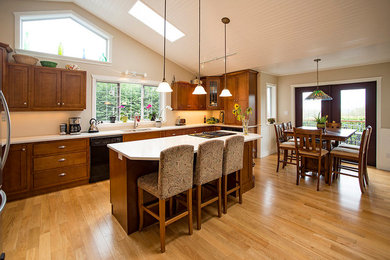 Example of a mid-sized country u-shaped light wood floor and brown floor eat-in kitchen design in Vancouver with an undermount sink, shaker cabinets, medium tone wood cabinets, quartz countertops, an island, stainless steel appliances and beige backsplash