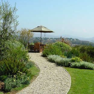 Exemple d'un jardin arrière méditerranéen avec du gravier et des bordures.