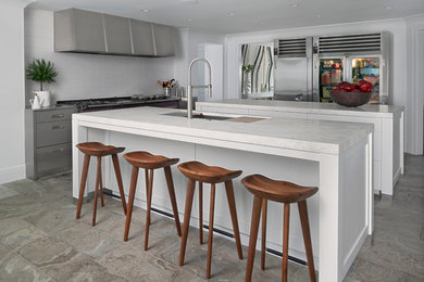 Example of a transitional l-shaped gray floor kitchen design in Detroit with an undermount sink, flat-panel cabinets, white cabinets, white backsplash, stainless steel appliances, two islands and white countertops