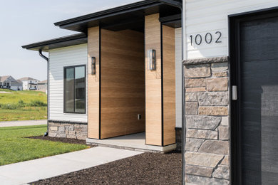 Inspiration for a transitional concrete floor and wood wall entryway remodel in Other with brown walls and a black front door