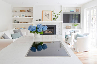 Example of a large trendy open concept light wood floor and brown floor family room design in Vancouver with white walls, a standard fireplace, a stone fireplace and a wall-mounted tv