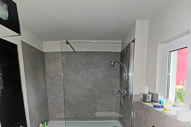 Modernes Badezimmer mit bodengleicher Dusche, grauen Fliesen und Betonboden in Sonstige