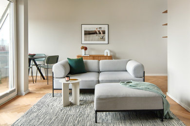 Kleines, Offenes Modernes Wohnzimmer in grau-weiß mit grauer Wandfarbe, hellem Holzboden und TV-Wand in Berlin