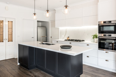 Photo of a mid-sized kitchen in Melbourne with an undermount sink, shaker cabinets, quartz benchtops, white splashback, porcelain splashback, stainless steel appliances, dark hardwood floors and with island.