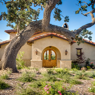 サンタバーバラの大きい両開きドアサンタフェスタイルのおしゃれな玄関 (ベージュの壁、淡色木目調のドア) の写真