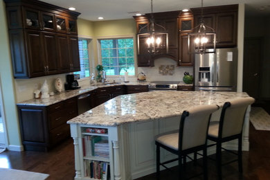Mid-sized elegant l-shaped dark wood floor eat-in kitchen photo in Other with an undermount sink, raised-panel cabinets, dark wood cabinets, granite countertops, beige backsplash, ceramic backsplash, stainless steel appliances and an island