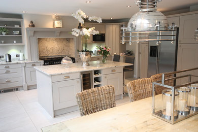 Photo of a large classic open plan kitchen in Other with a belfast sink, shaker cabinets, grey cabinets, granite worktops, grey splashback, stone slab splashback, stainless steel appliances, travertine flooring and an island.