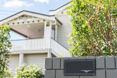 Photo of a mid-sized two-storey white house exterior in Brisbane with a butterfly roof and a grey roof.
