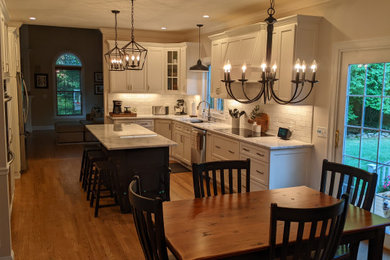 Inspiration for a large timeless l-shaped medium tone wood floor and brown floor eat-in kitchen remodel in Boston with an undermount sink, shaker cabinets, white cabinets, granite countertops, gray backsplash, subway tile backsplash, stainless steel appliances, an island and white countertops