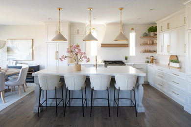 Example of a mid-sized transitional l-shaped medium tone wood floor and brown floor eat-in kitchen design in Minneapolis with an undermount sink, shaker cabinets, white cabinets, quartz countertops, white backsplash, porcelain backsplash, stainless steel appliances, an island and white countertops
