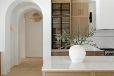 Kitchen - huge modern wood ceiling kitchen idea in Phoenix with glass-front cabinets, light wood cabinets, white backsplash, stone slab backsplash, paneled appliances, two islands and white countertops