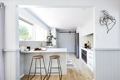 Design ideas for a small beach style u-shaped eat-in kitchen in Sydney with shaker cabinets, white cabinets, quartz benchtops, grey splashback, a peninsula and grey benchtop.
