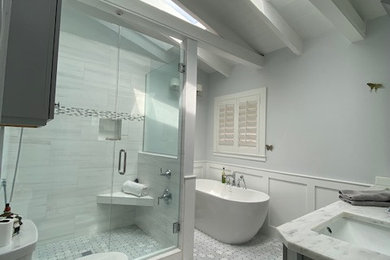 Large transitional master white tile and marble tile double-sink, shiplap ceiling, wainscoting and gray floor bathroom photo in Miami with a built-in vanity, shaker cabinets, gray cabinets, white walls, an undermount sink, marble countertops, a hinged shower door, white countertops and a two-piece toilet