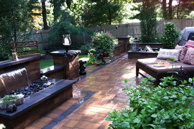 This is an example of a modern backyard patio in New York with a water feature and concrete pavers.