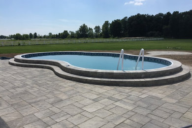 This is an example of a small traditional backyard kidney-shaped lap pool in New York with stamped concrete.