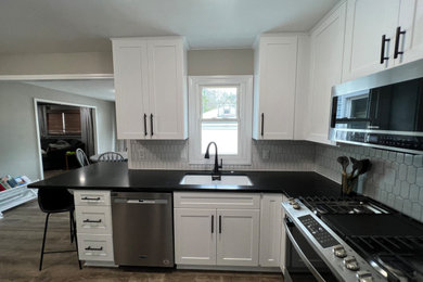 Inspiration for a mid-sized transitional l-shaped vinyl floor eat-in kitchen remodel in Cleveland with shaker cabinets, white cabinets, granite countertops, white backsplash and black countertops
