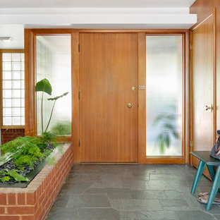 ポートランドの中サイズの片開きドアミッドセンチュリースタイルのおしゃれな玄関ロビー (白い壁、スレートの床、木目調のドア、緑の床) の写真