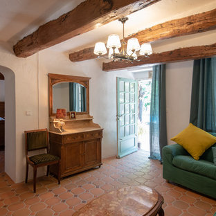 Imagen de salón mediterráneo con paredes blancas, suelo de baldosas de terracota y suelo rojo