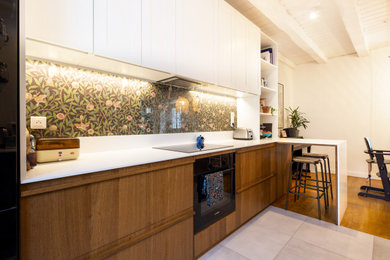 Medium sized traditional galley open plan kitchen in Nantes with an integrated sink, shaker cabinets, brown cabinets, composite countertops, multi-coloured splashback, glass sheet splashback, stainless steel appliances, ceramic flooring, a breakfast bar, grey floors, white worktops and exposed beams.