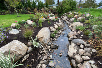 Design ideas for a mid-sized beach style front yard full sun xeriscape in New York with with rock feature and river rock.