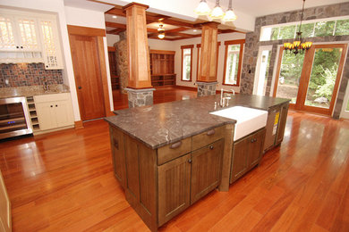 Open concept kitchen - mid-sized craftsman l-shaped medium tone wood floor open concept kitchen idea in DC Metro with glass-front cabinets, beige cabinets, granite countertops, beige backsplash, paneled appliances and an island